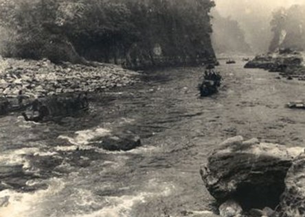 Small wooden boats navigating down a rocky river to transport supplies